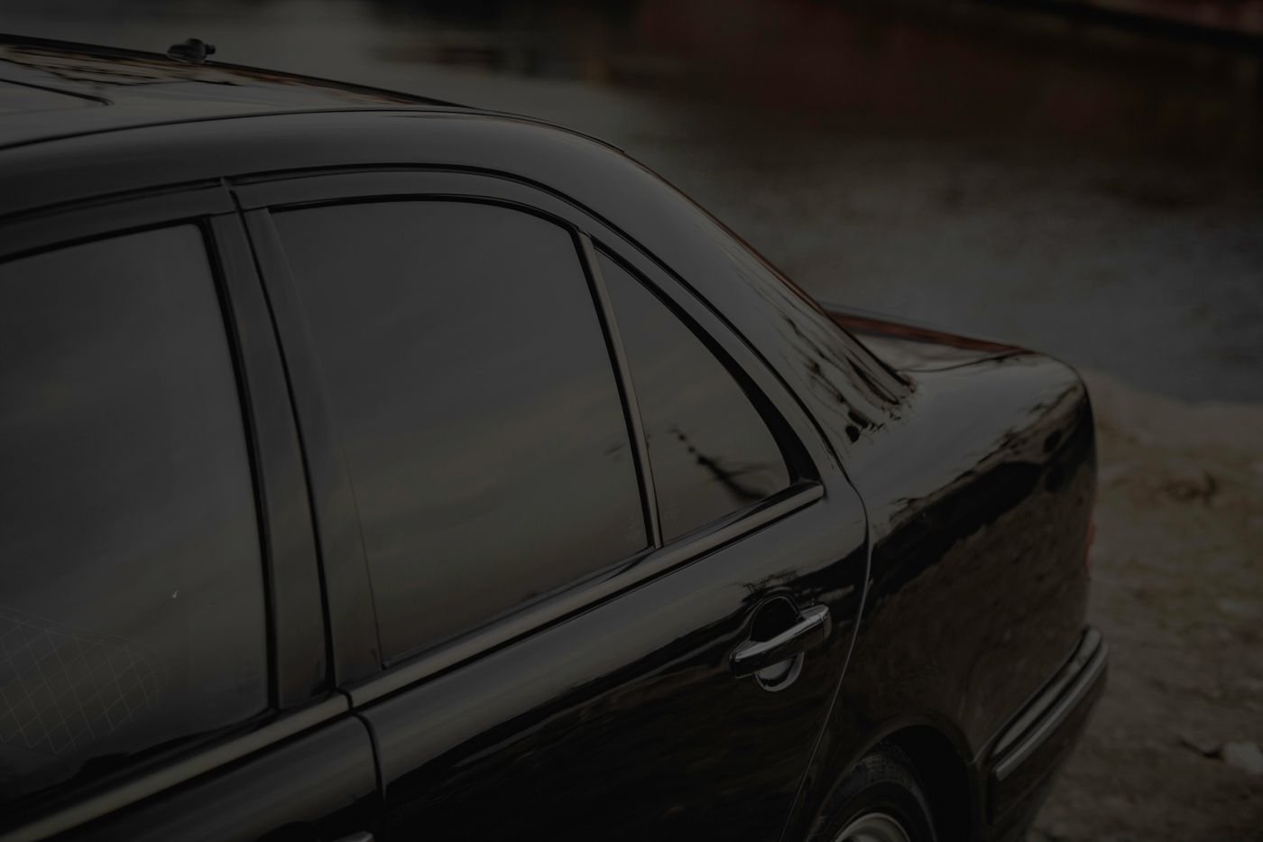Close side view of a black sedan with dark tinted windows